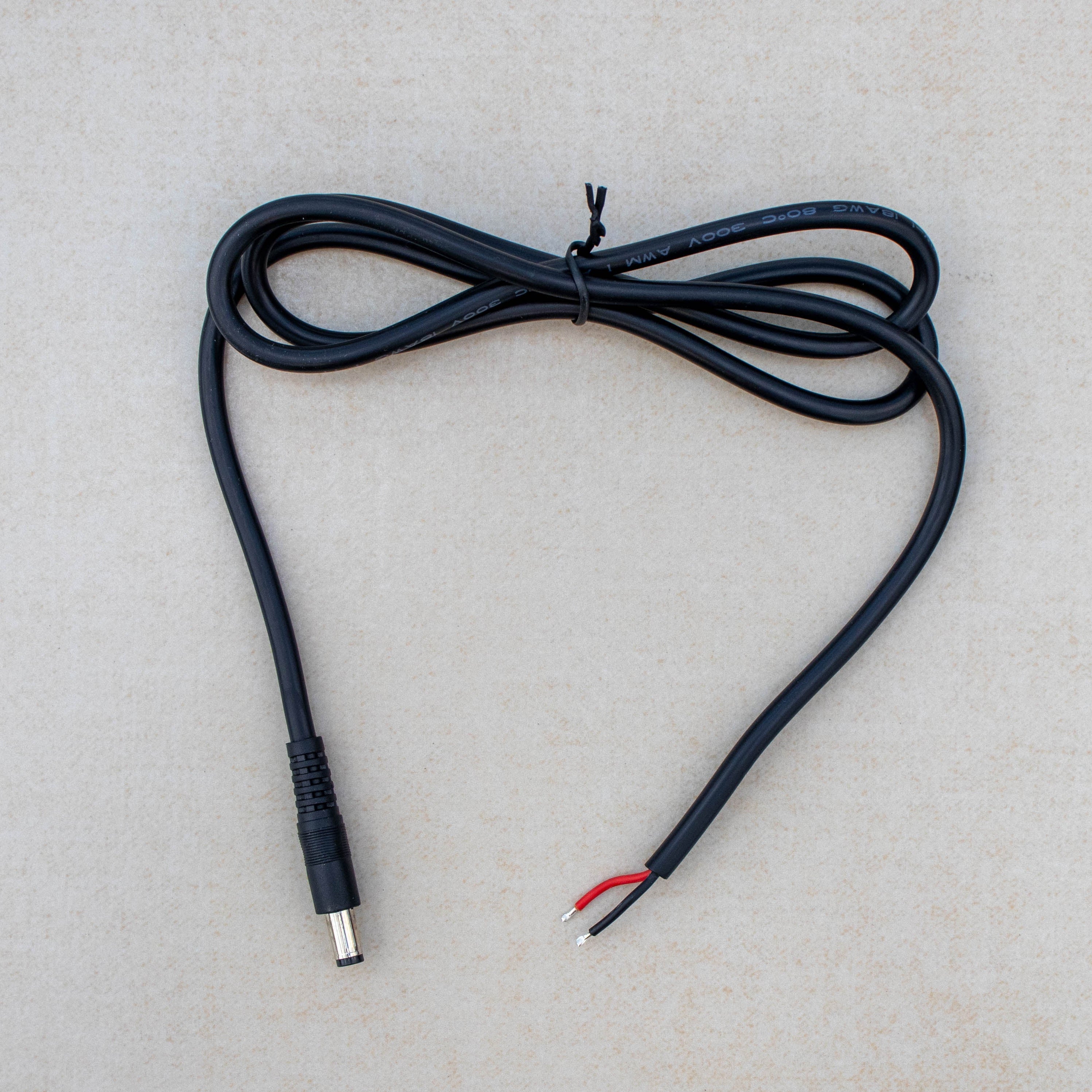Black electrical cable with plug on a light gray background